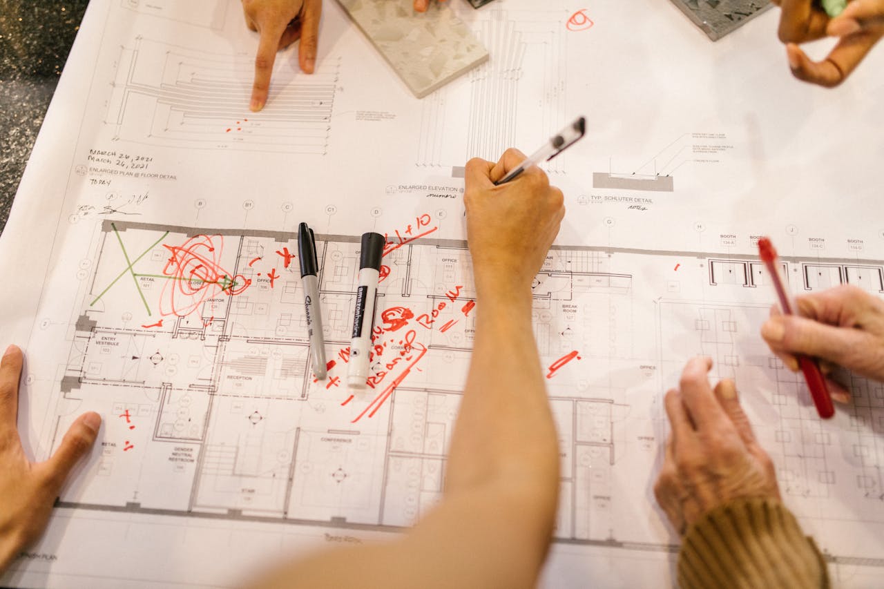 about-01 Team working together on architectural blueprints, marking plans with red ink.